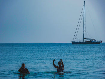 People swimming in sea against clear sky