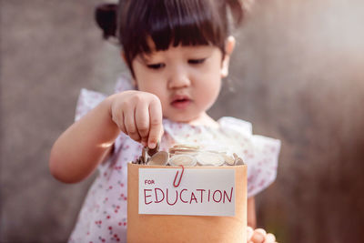 Close-up of girl putting coins in cardboard box