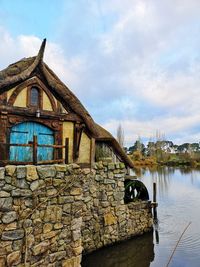 Old building by lake against sky