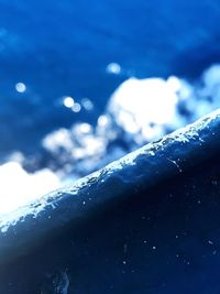 Close-up of snow covered water against blue sky