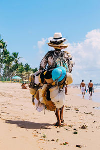 Rear view of male street vendor selling hat at beach