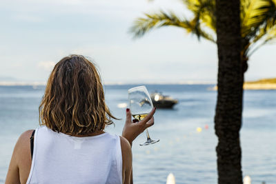 Woman having wine at beach against sky