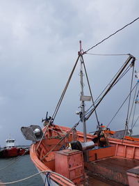 Boats moored at commercial dock against sky