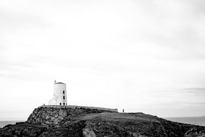 Lighthouse by sea against sky