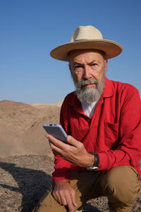 Vertical view of senior man using mobile phone in the desert 