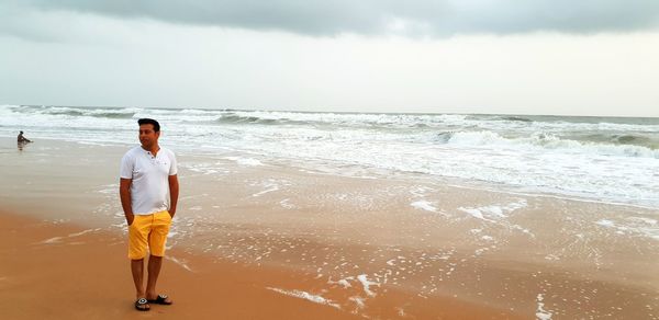 Full length of woman standing on beach against sky