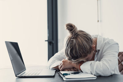 Rear view of woman using laptop at home