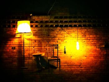 Illuminated lamp against wall at night