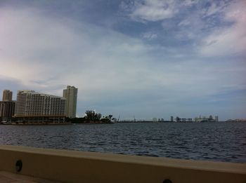 City buildings by sea against sky