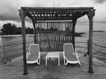 Empty chairs on beach against sky