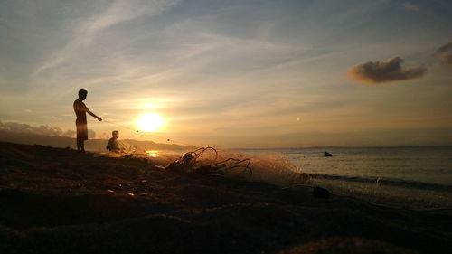 Man standing on beach against sky during sunset