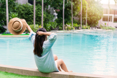 Rear view of woman sitting on retaining wall