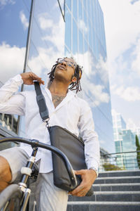 Man holding umbrella in city against sky