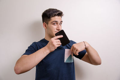 Young man looking away while standing against white background