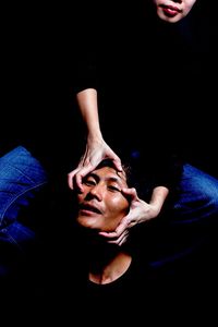 Close-up of couple hands against black background