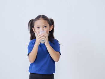 Portrait of girl drinking water against white background