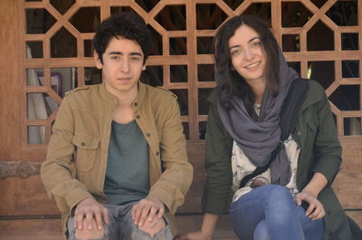 Portrait of friends sitting on steps against door