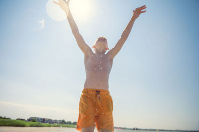 Midsection of woman with arms raised standing against sky