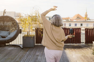 Rear view of senior woman dancing while listening music on terrace