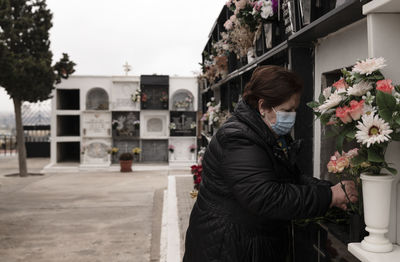 Old lady with mask mourning her family in cemetery. almeria, spain