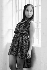 Portrait of young woman standing against wall