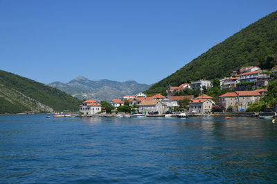 Houses by buildings in town against clear blue sky