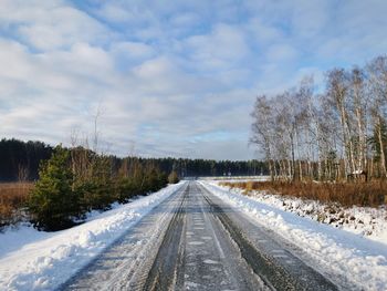 Road amidst trees against sky during winter