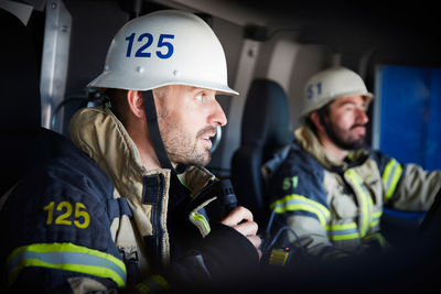 Firefighter talking on microphone while sitting with coworker in fire engine