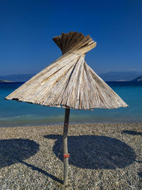 Traditional windmill on beach against clear blue sky