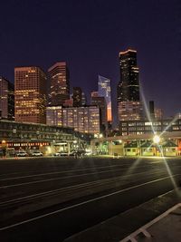 Illuminated modern buildings in city against sky at night