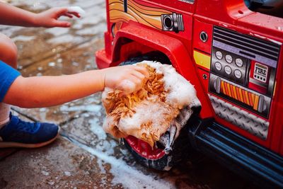 Hand of boy washing toy outdoors