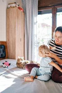 Young woman sitting on bed at home