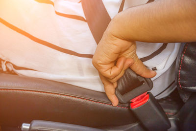 Close-up midsection of man fastening seat belt in car