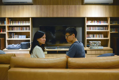 Couple sitting on sofa in living room at home