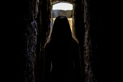 Silhouette woman standing in alley amidst walls