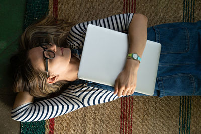 High angle view of woman with laptop lying on carpet