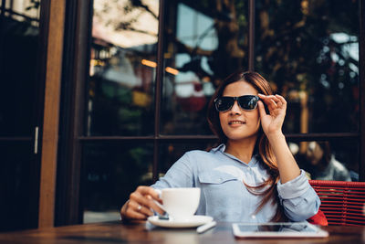 Close-up of young woman sitting on table at cafe