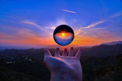 Person hand against sky during sunset