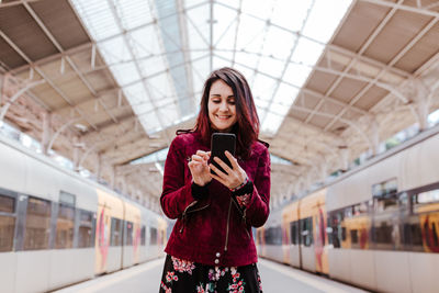Full length of young woman using mobile phone