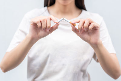Midsection of woman holding hands against white background