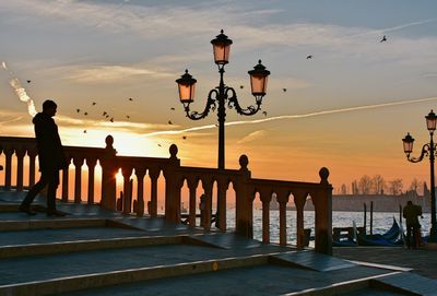 Side view full length of man by railing on steps during sunset