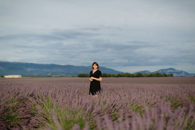 Full length of woman standing on field against sky