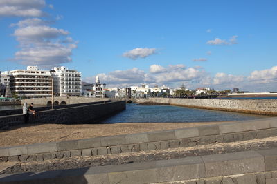 View of retaining wall by sea against blue sky