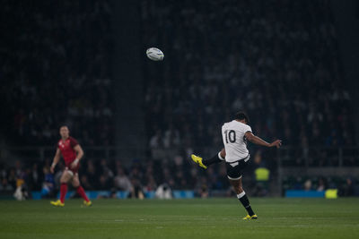 Low angle view of people on soccer field at night