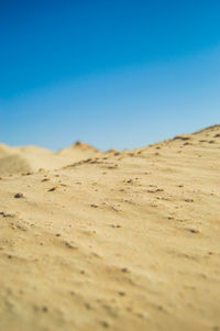 Surface level of desert against clear blue sky