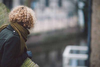 Side view of woman wearing warm clothing while looking away in city