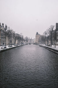 Bridge over river in city against clear sky