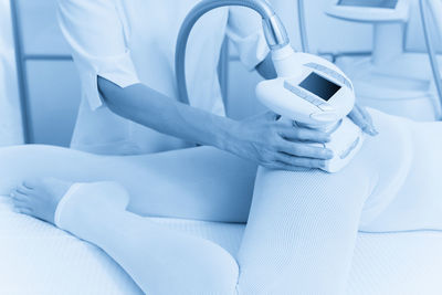 Midsection of woman using mobile phone while lying on bed at home