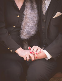 Midsection of couple in suit sitting on seat