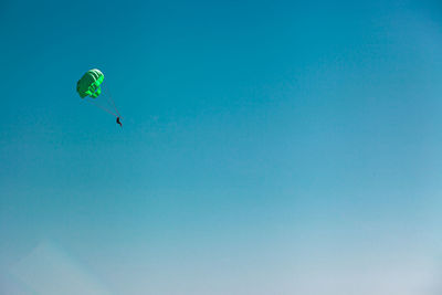 Low angle view of person paragliding against clear blue sky